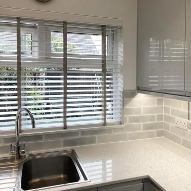 Modern kitchen with a sink, grey cabinets, and window with blinds.