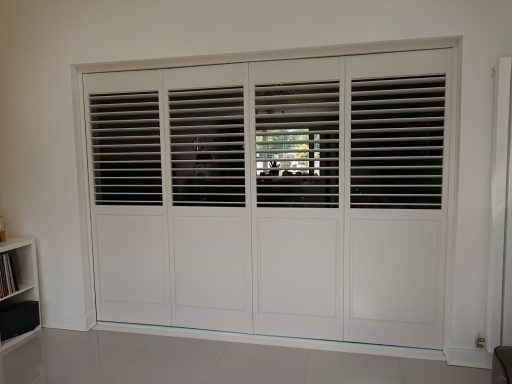 White sliding door with horizontal slats, partially open to reveal a window behind.