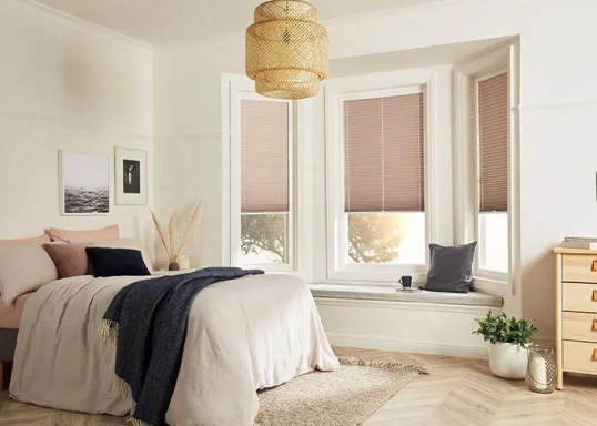 Cozy bedroom with a bed, wooden dresser, and large windows featuring elegant blinds.