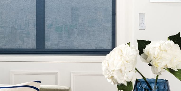 White flowers in a vase near a window with a cityscape view through frosted glass.