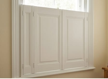 White wooden shutters closed over a window in a beige wall.