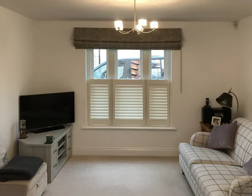 Bright living room featuring a sofa, TV, and window with shutters.