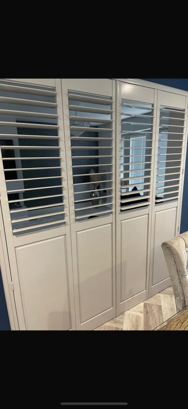 White wooden shutters with horizontal slats in a room setting.