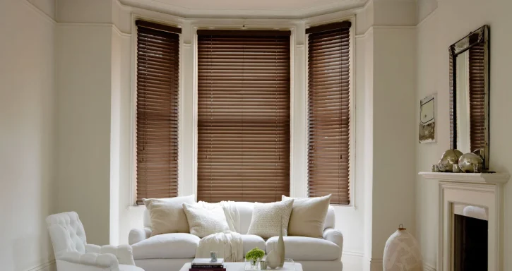 Bright living room with a white sofa, brown window blinds, and a decorative fireplace.