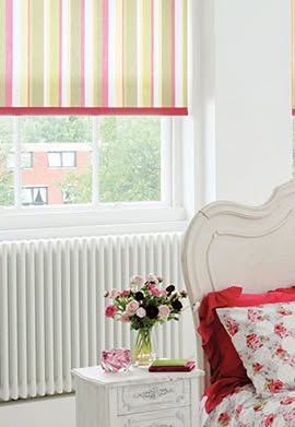Brightly decorated room with striped blinds, a floral bedspread, and a vase of flowers.